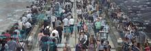 Shot from a security camera perspective, the image depicts a dense crowd of commuters. Each commuter is represented by a point of light connected to a vast wifi network.  